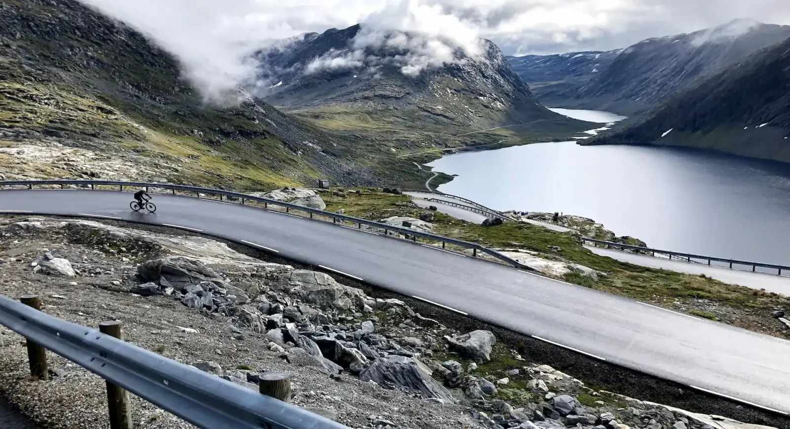 Cyclist descending Dalsnibba with Norwegian fjord panorama