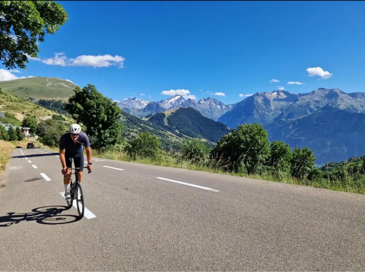 Rennradfahrer auf Alpe d'Huez mit Blick über die Serpentinen und das Massif des Écrins im Oisans, Frankreich.