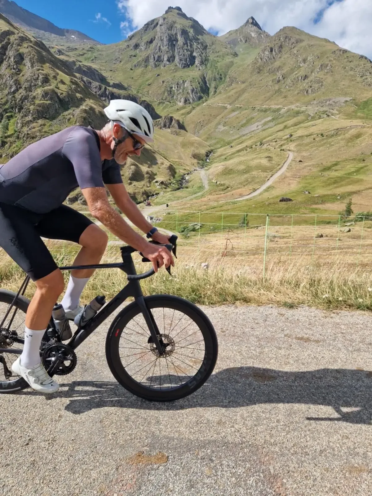 Aero bike, dry grass and jagged Oisans summits behind