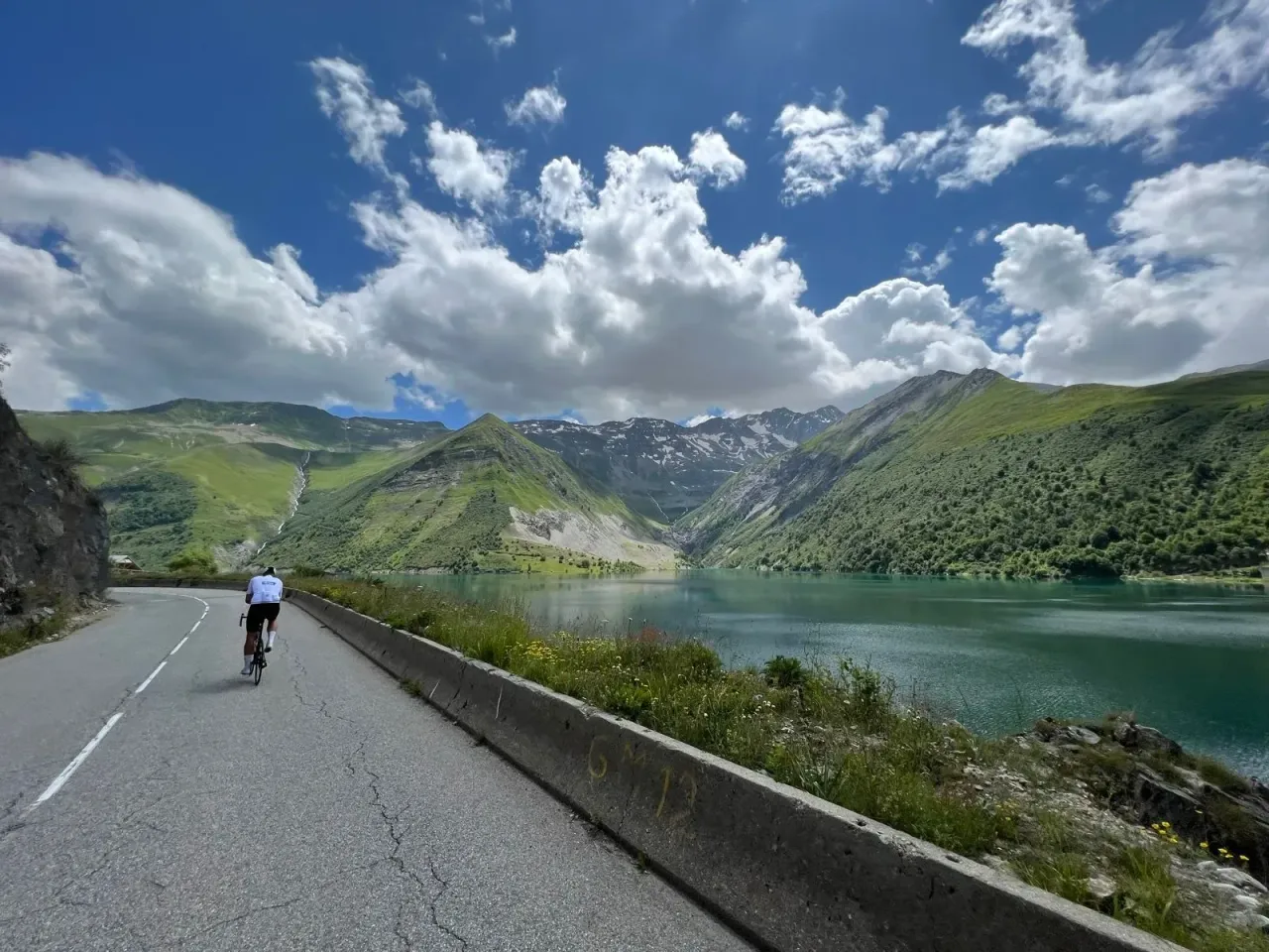 Abfahrt am türkisfarbenen Lac de Grand Maison auf der Croix-de-Fer–Glandon-Runde, Französische Alpen.