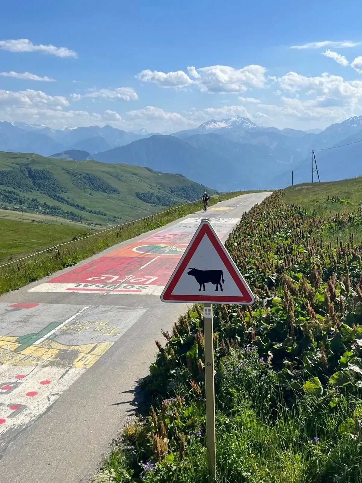 Col de la Madeleine summit sign at 2,000 m on the D213, Savoie, French Alps, with alpine peaks behind.
