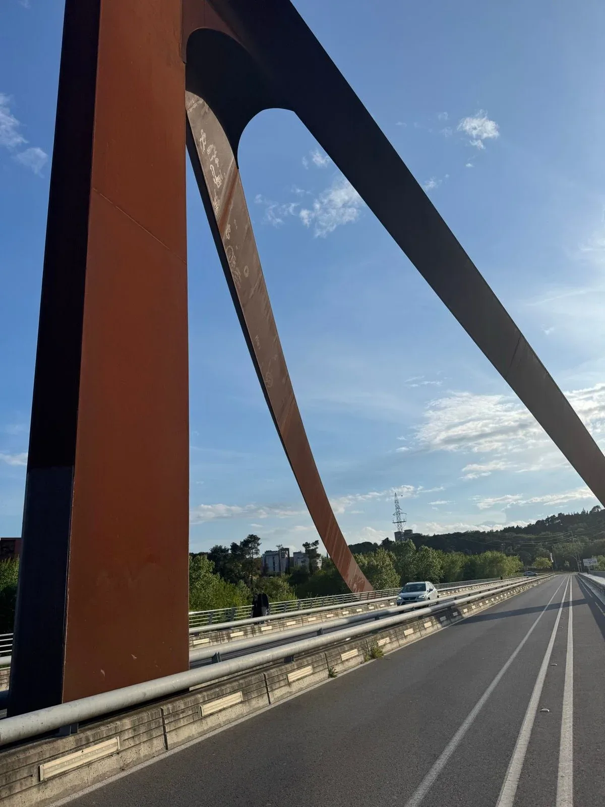 The orange steel pylon of the Pont del Dimoni against a bright Catalan sky.