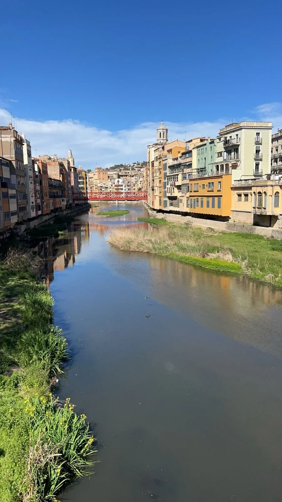 Pastel façades and the red Pont de les Peixateries Velles on the Onyar.