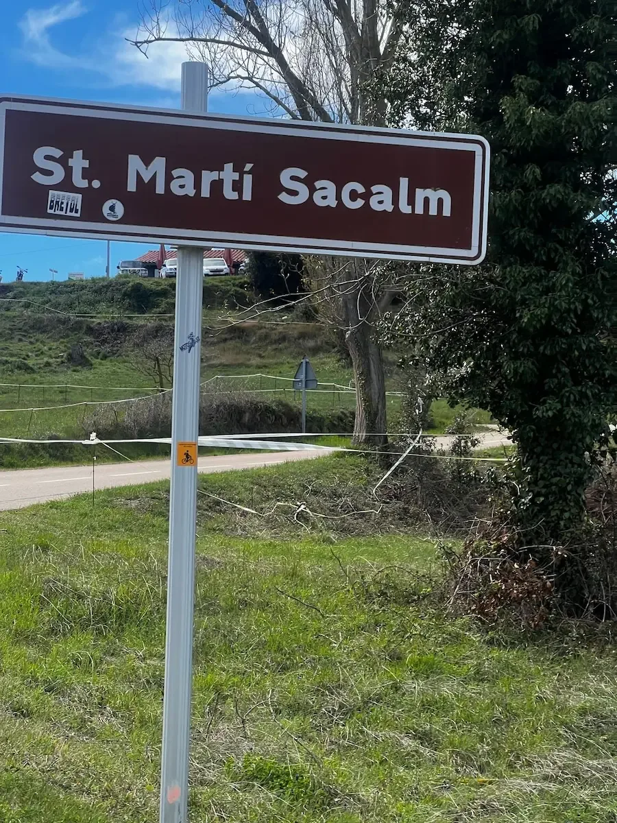 The brown village sign for St. Martí Sacalm at the top of the climb.