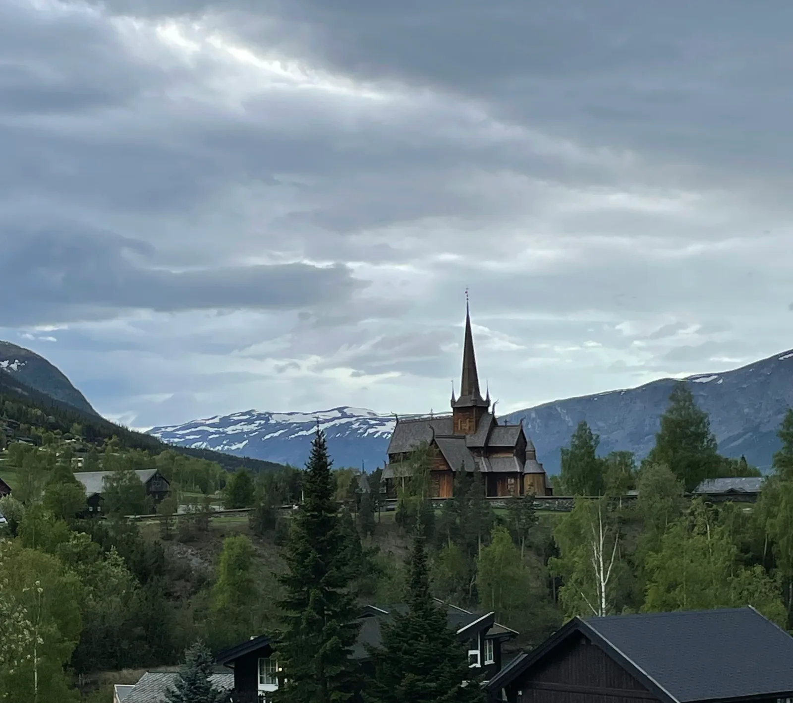 Lom stavkyrkje against snow-streaked Jotunheimen peaks.