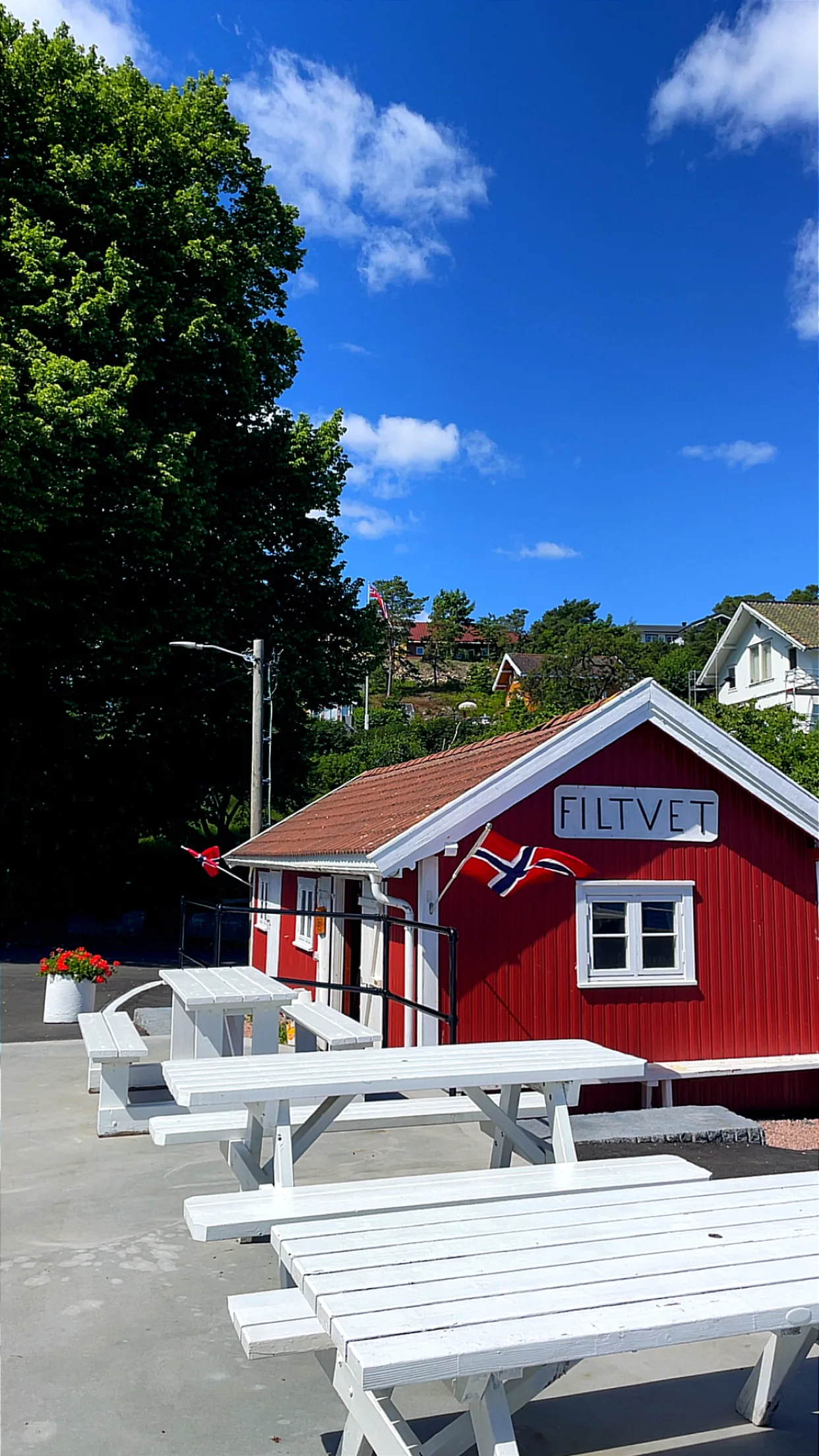 La pequeña caseta-café roja del muelle de Filtvet, con bancos blancos y bandera.