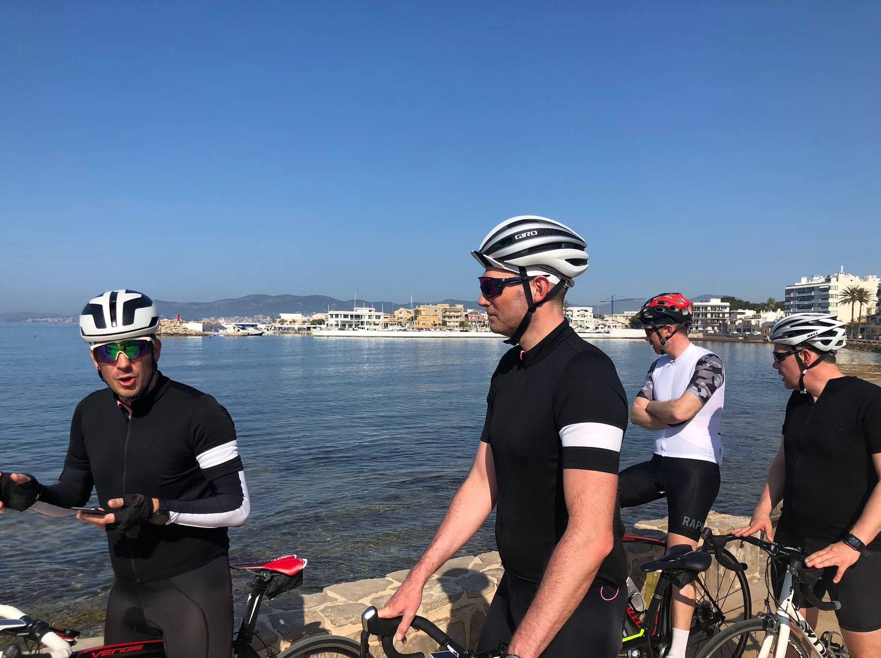 Cycling group taking a break at a Mallorca harbour on a clear spring morning